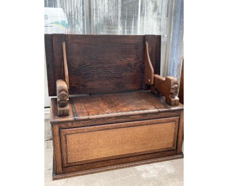 AN OAK MONK'S BENCH WITH CARVED ARMRESTS AND UNDER SEAT COMPARTMENT - CONVERTS TO A TABLE 