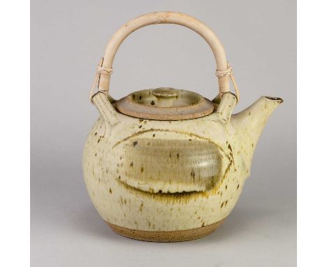 † MICHAEL CASSON (1925-2003); a large stoneware teapot with cane handle covered in oatmeal glaze with iron brush decoration, 