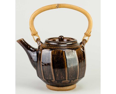 † MIKE DODD (born 1943); a faceted stoneware teapot with cane handle covered in tenmoku breaking to kaki glaze, impressed MJD