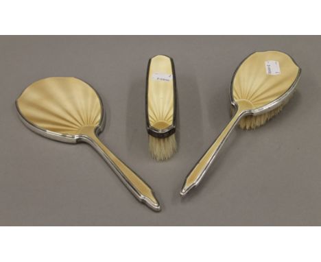 Two silver and enamel brushes, and a mirror. The latter 28 cm long.
