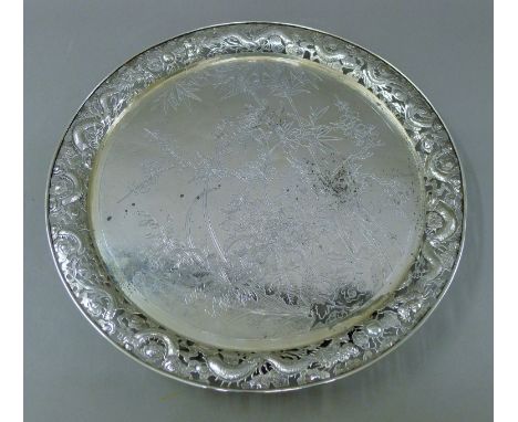 A Chinese silver tray, the pierced border decorated with dragons chasing a flaming pearl. 37 cm diameter. 40.4 troy ounces.  