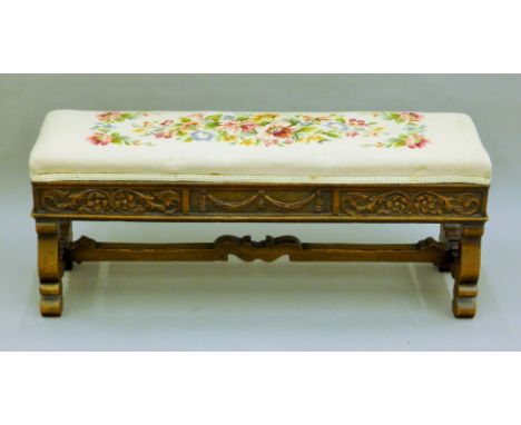 A carved oak stool with tapestry cover. 102.5 cm long.