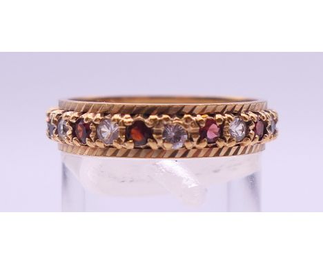 A 9 ct gold gem set full eternity ring. Ring size Q/R. 3.6 grammes total weight.