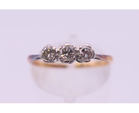 An 18 ct gold and platinum three stone diamond ring. Ring size M. 