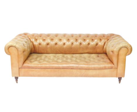 A Victorian style Chesterfield sofa, upholstered in button back tan leather, raised on turned oak feet, brass capped on caste