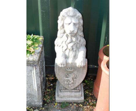 A concrete garden figure of a lion, modelled rampant holding an armorial shield, on a step square base, 85cm.