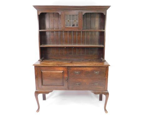 A Victorian oak dresser, the plate rack with outswept pediment over a central stained glass door, flanked by shelves, over a 