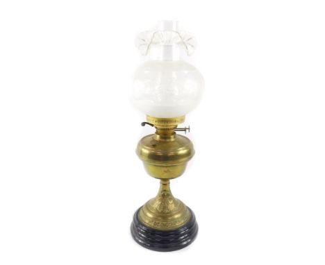 A Duplex early 20thC brass oil lamp, embossed with flowers, raised on a black ceramic socle, with chimney and frilled frosted