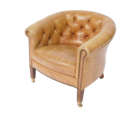 A Victorian style mahogany framed tub armchair, upholstered in button back tan leather, raised on tapering square legs brass 