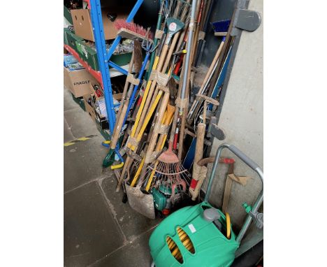 A large quantity of garden tools including rakes, brushes, spades, forks, hozelock portable garden hose reel, and a petrol st