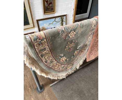 An oval Chinese wool carpet, green ground decorated with flowers, length 175cm 