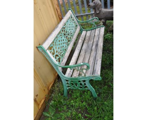 A WOODEN SLATTED GARDEN BENCH with cast iron ends and back panel 127cm wide (Condition weathered finish slightly rickety)