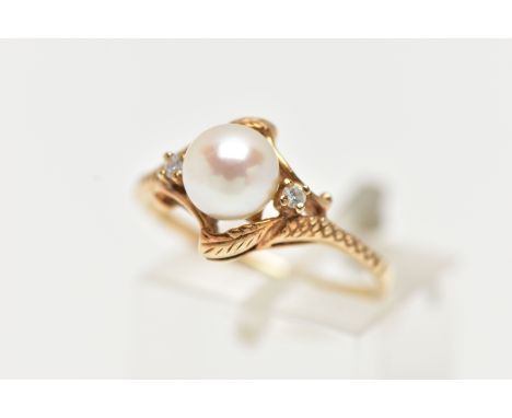 A YELLOW METAL CULTURED PEARL RING, designed with a single cultured cream pearl with a pink hue to the centre, flanked with t