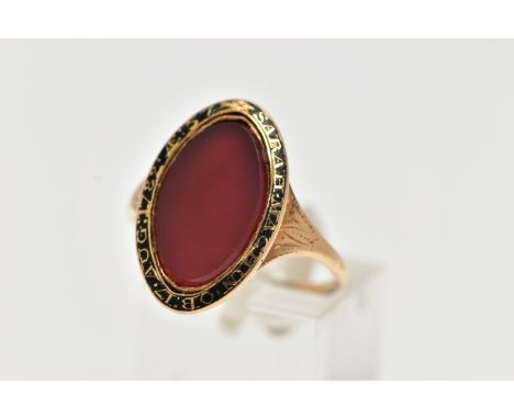 A YELLOW METAL AND CARNELIAN MOURNING RING, of an oval form, set with a central oval cut polished carnelian inlay, within a b