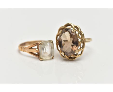 A 9CT GOLD SMOKY QUARTZ RING AND A QUARTZ RING, the first a large oval cut smoky quartz, set within a yellow gold open work t