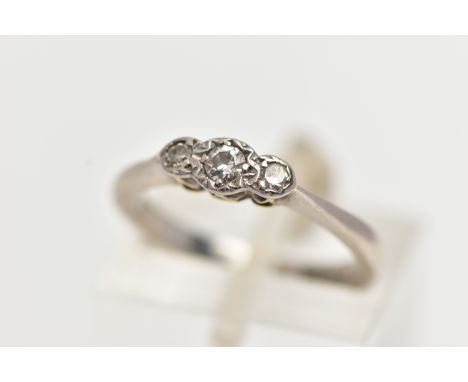 A WHITE METAL THREE STONE DIAMOND RING, to the centre sits a round brilliant cut diamond in an illusion setting, flanked with