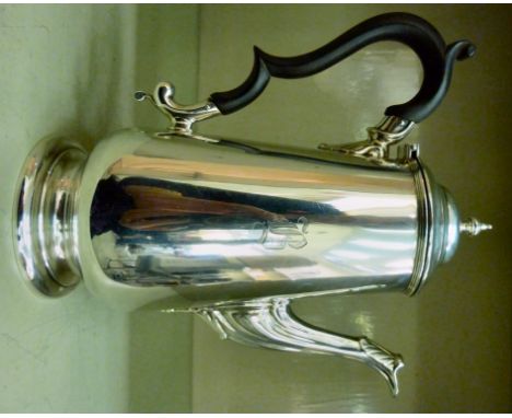 A Georgian style silver coffee pot of tapered form, having a foliate cast, swept spout, a C-scrolled ebonised handle and an o