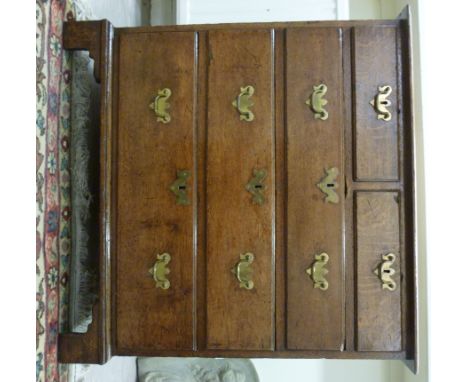 An early 19thC light oak dressing chest, having two short/three graduated long drawers with brass bail handles on pierced bac