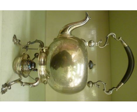 A Georgian style silver tea kettle of ovoid form, having a swept spout, a folding top handle with an ebonised grip, a flush f