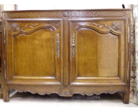 A mid 18thC French oak cabinet, having a carved frieze and twin panelled doors with foliate and starburst carved decoration, 