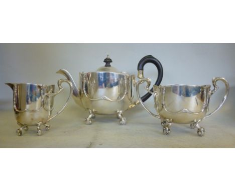 An Edwardian three piece silver tea set of bowl design with cast and applied ornament, on scrolled feet, the teapot having a 