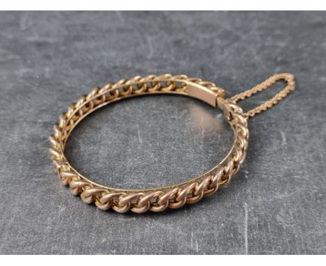 A yellow metal hinged bangle, stamped 9c, 58mm maximum internal diameter. 