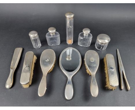 An engine turned silver dressing table set, comprising: four brushes, a mirror, a shoe horn, five silver lidded jars; and a p