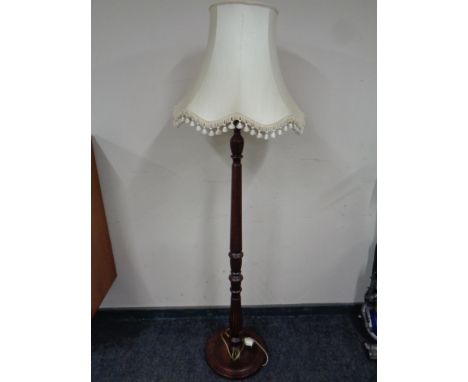 A carved beechwood standard lamp with tasselled shade  