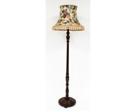 An oak standard lamp, with floral shade, on a part fluted stem, on a circular layered base, 70cm high.