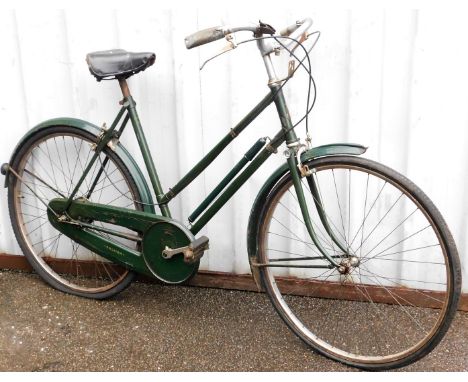 A Sturmey Archer geared vintage ladies bicycle, with a green frame on a black leather seat.