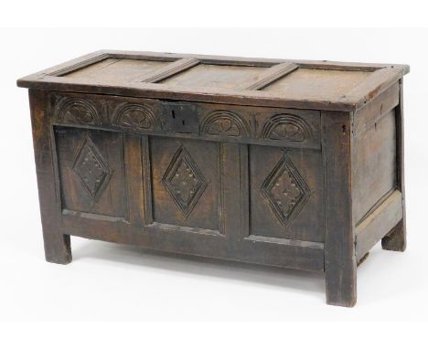 A late 17th/early 18thC oak coffer, the three panelled top section with metal hinges, on a carved two panel front with shield