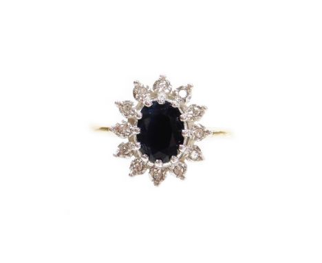 A 9ct gold cluster ring, with central dark blue stone surrounded by various cz stones, on a raised white gold setting on a ye