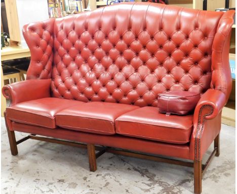 A Chesterfield style three seater chair, the red button back upholstery, on a mahogany base, 130cm high, 180cm wide, 90cm dee