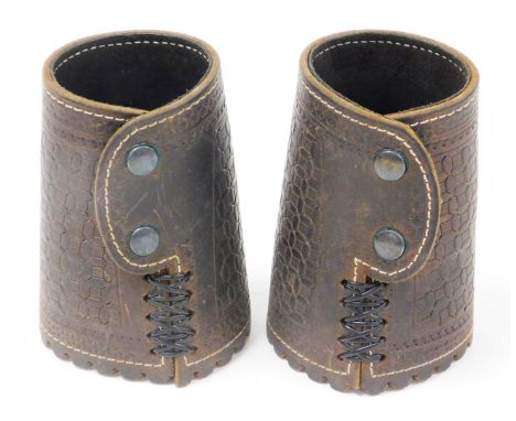 A pair of American leather arm cuffs, each with straps and two button design, 17cm high.