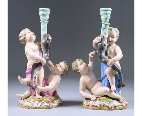 A Pair of Meissen Porcelain Figural Candlesticks, 19th Century, each modelled as two putti holding aloft a fish biting a tree