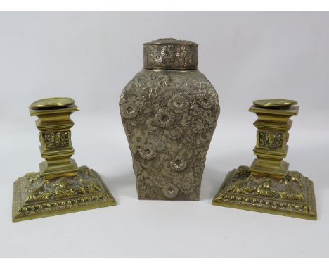 Pair of highly decorated brass candlesticks (3.5") and a white metal tea caddy, 6".
