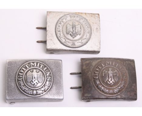 Three German Army Belt Buckles consisting of a steel pattern example with remains of the green combat paint finish, two piece