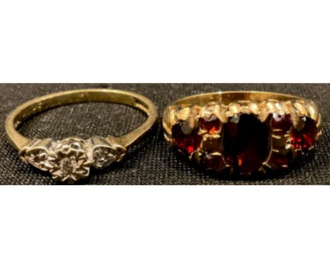 A 9ct gold illusion set three stone ring, size N, marked 375, tests as diamond, 1.8g; a 9ct gold seven stone garnet ring, siz