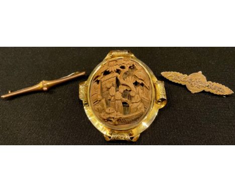 A 19th century unmarked metal oval brooch, the central wooden oval Chinoiserie panel carved in relief with figures in a garde