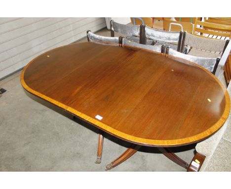A reproduction mahogany and satin wood cross banded twin pillar dining table