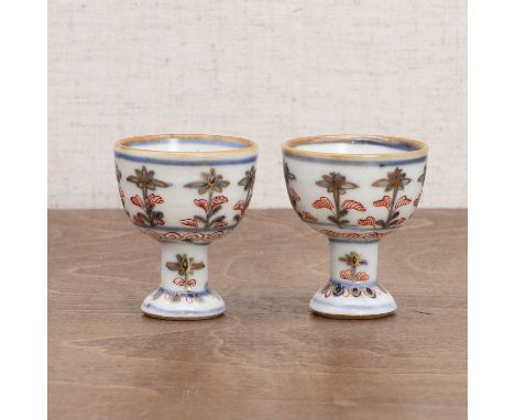 A pair of Chinese stem cups, Kangxi (1662-1722), each globular body raised on a high foot, painted with sprigs of florets in 