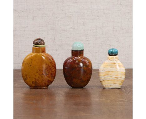 Three Chinese snuff bottles, Qing dynasty (1644-1911), plain, well hollowed with natural inclusions, comprising:two in jasper