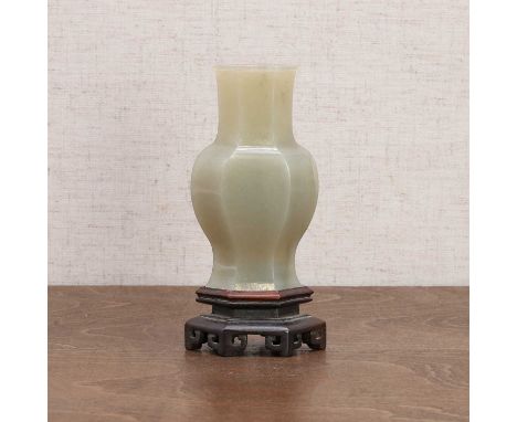 A Chinese jade vase, 20th century, of hexagonal baluster form, plain, the stone of greyish-white tone,9.3cm high, wood stand 