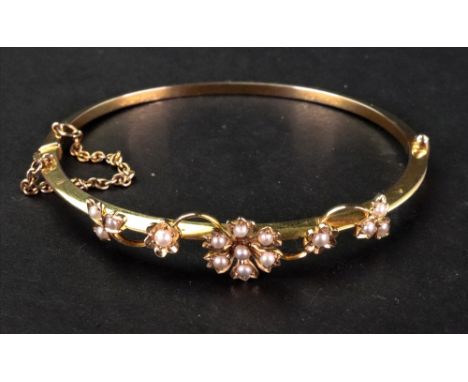 A gold and seed pearl oval hinged bangle, the central floral seed pearl decorating to knife edge oval bangle, complete with s