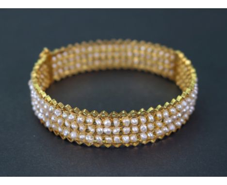 A gold and seed pearl hinged bangle, the seed pearls set in three rows with zig zag design to the top and bottom, 26.58g gros