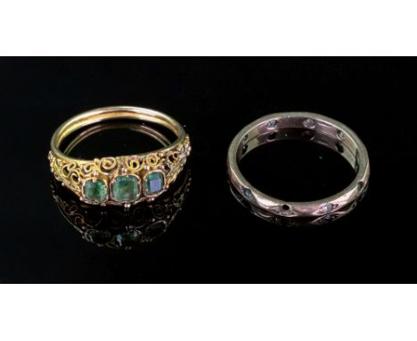 A gold and green gemset three stone ring, the stones set within millegrain scrolling detail and a gold and colourless paste e