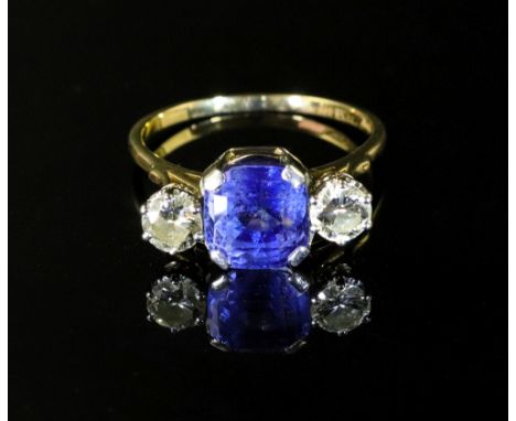 A gold, sapphire and diamond three stone ring, the octagonal cut sapphire in white claw settings between two round diamonds, 