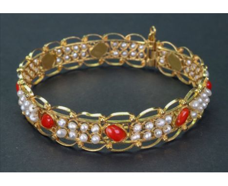 A gold, seed pearl and red gemset hinged bangle, the red cabochon gemstones set alternately between rows of seed pearls, 19.3