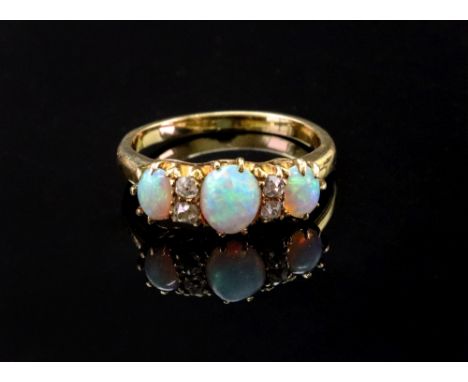 A gold, opal and diamond set ring, mounted with three oval opals and with two rows of cushion shaped diamonds mounted at inte