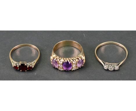 A gold, amethyst and colourless gemset ring, stamped 9CT, ring size S, a gold and diamond three stone ring, stamped 9CT, ring